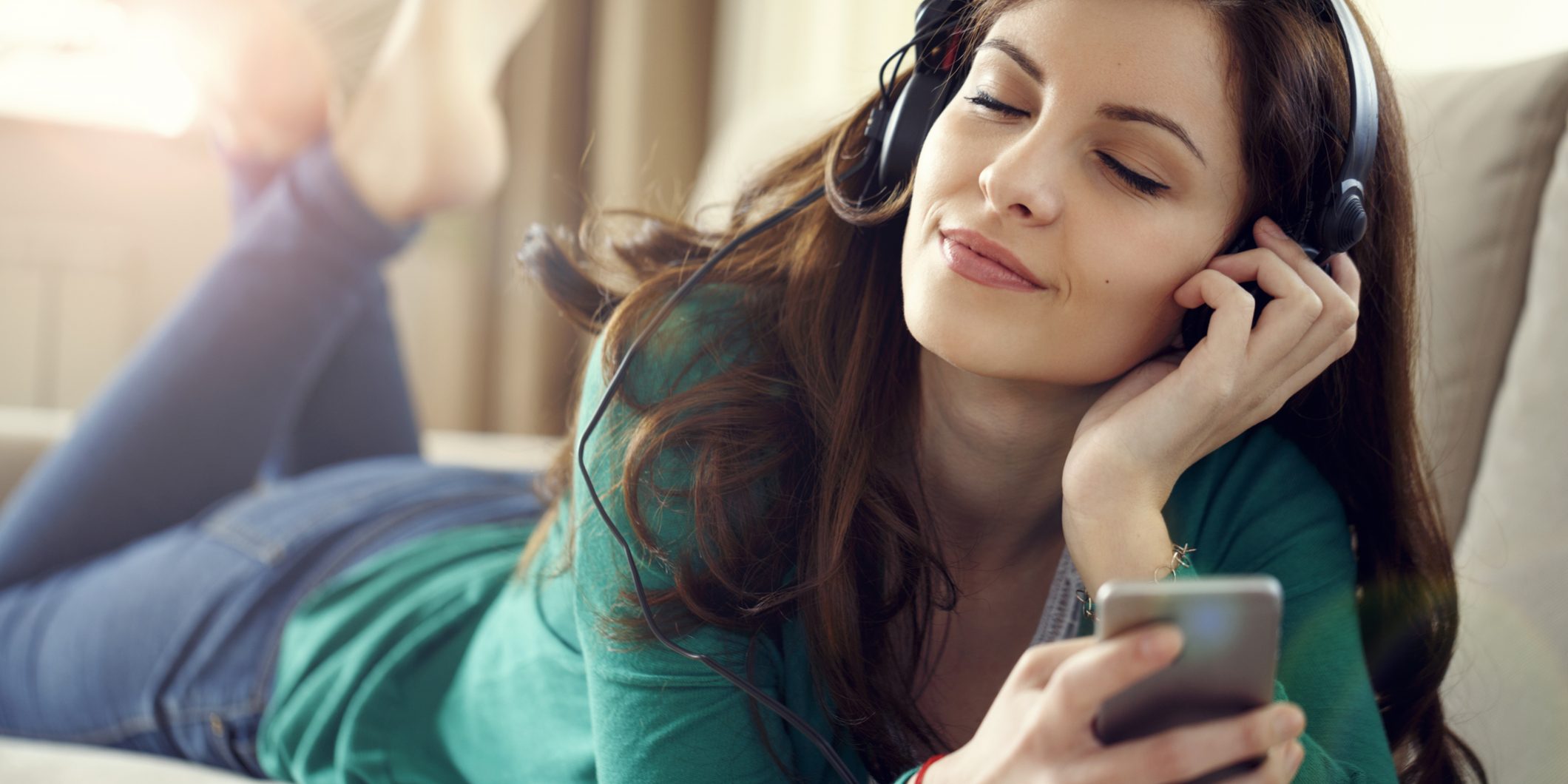 Attractive young woman with headphones listens music on smart ph