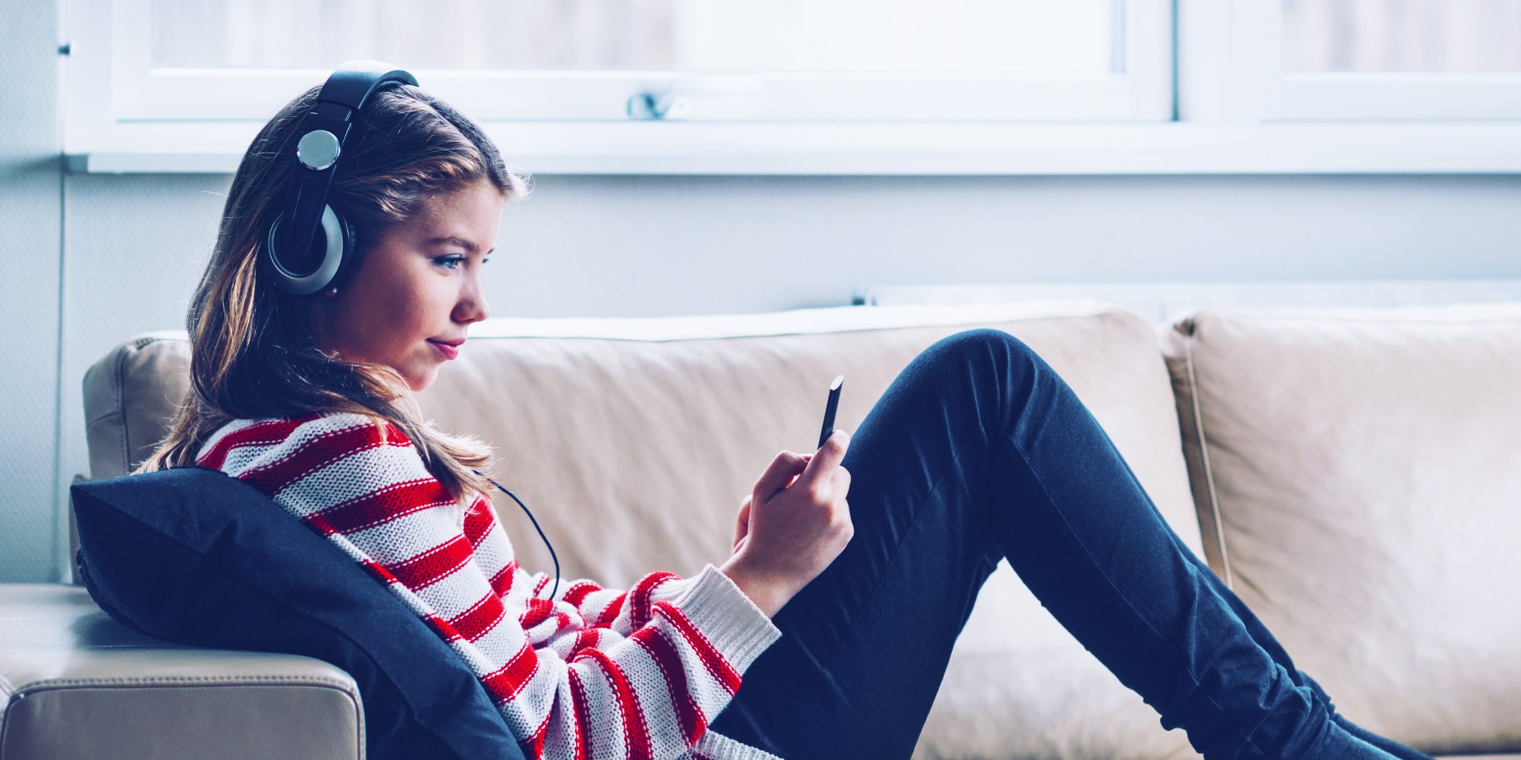 Teenage girls sits in sofa and listens to music or a podcast